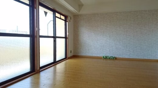 木目調フローリングと大きな窓のあるルミエール402号室のリビングルーム