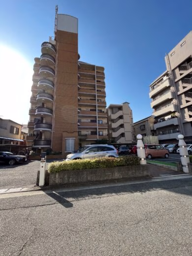 青空の下に立つ8階建てのルミエールの外観と駐車場
